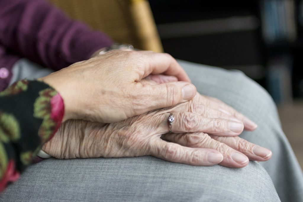 Elderly couple holding hands as they plan out their will