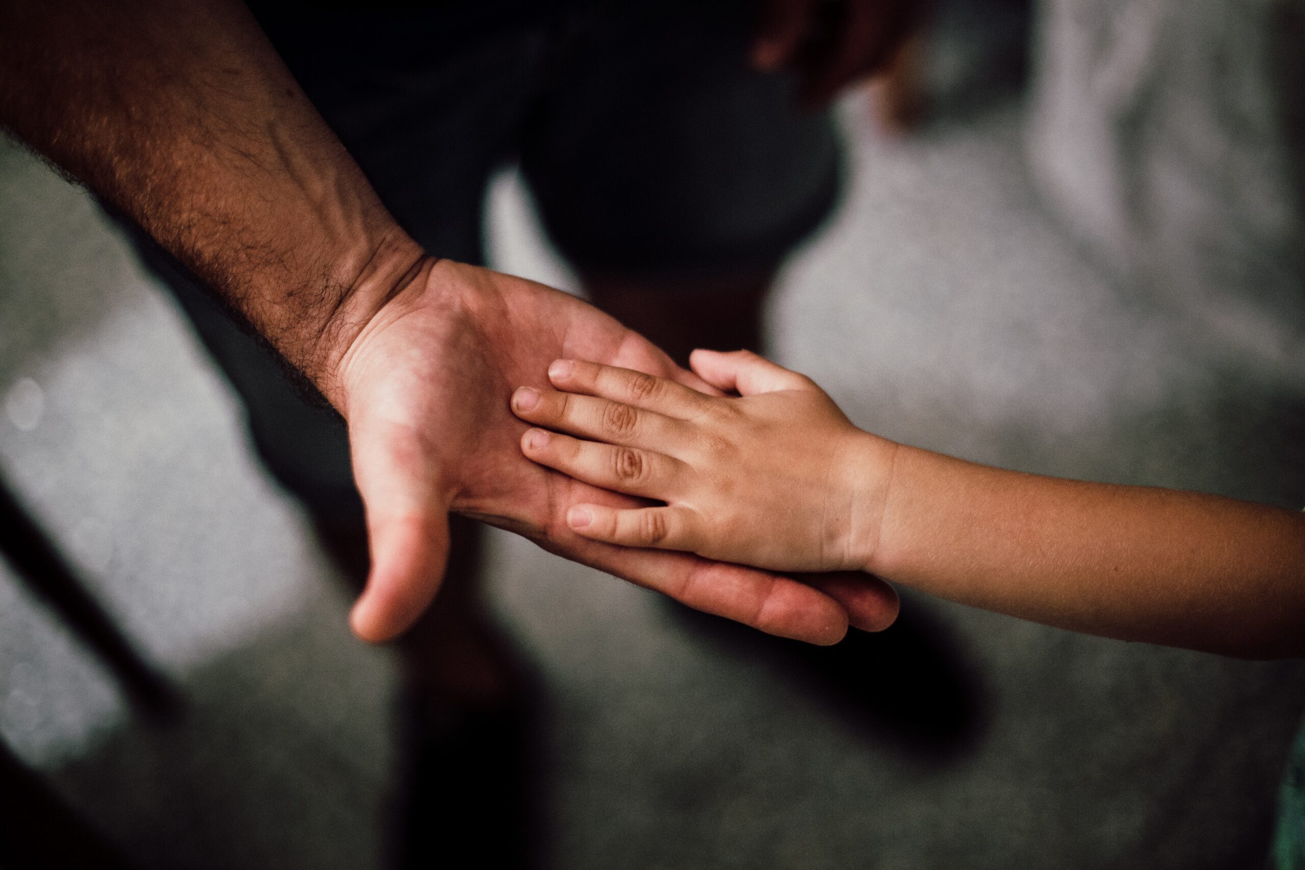 Child putting hand in father's palm