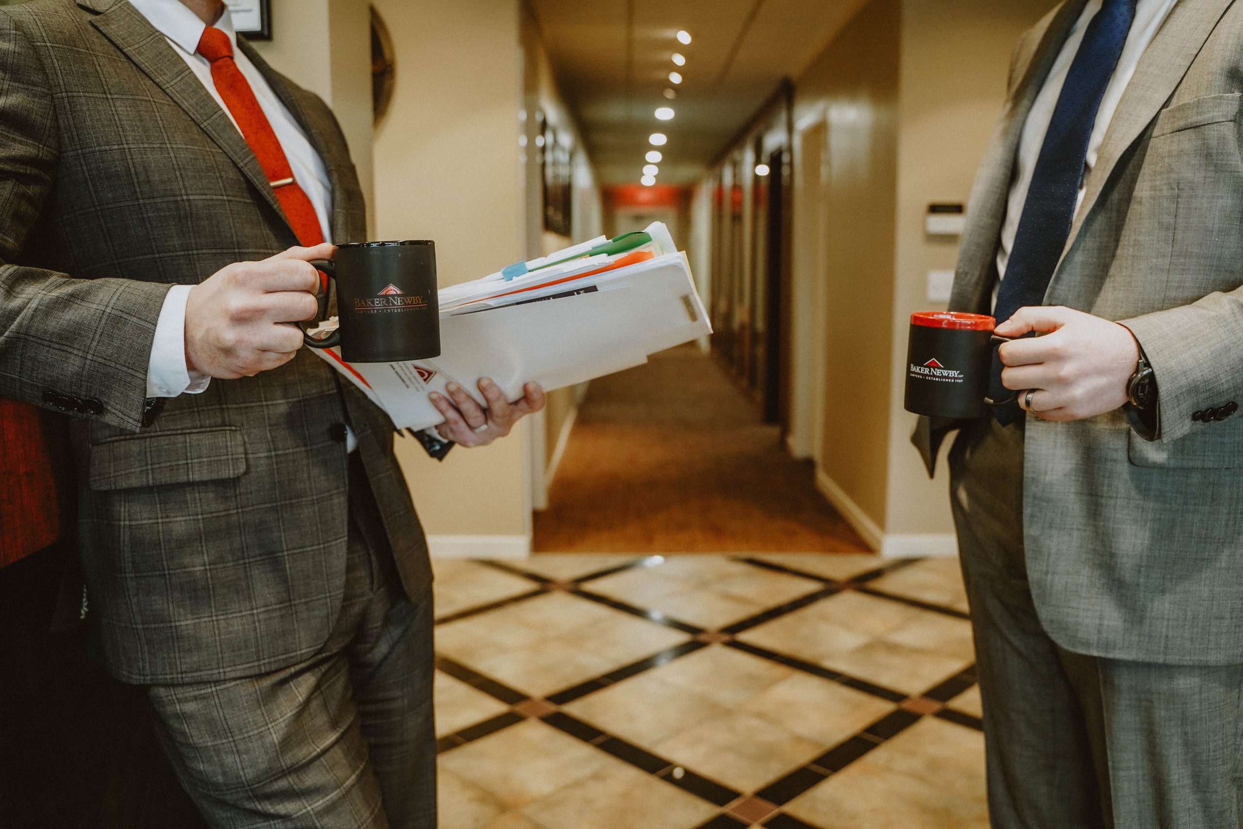 Baker Newby lawyers discussing a case in the hallway with a cup of coffee in their hands