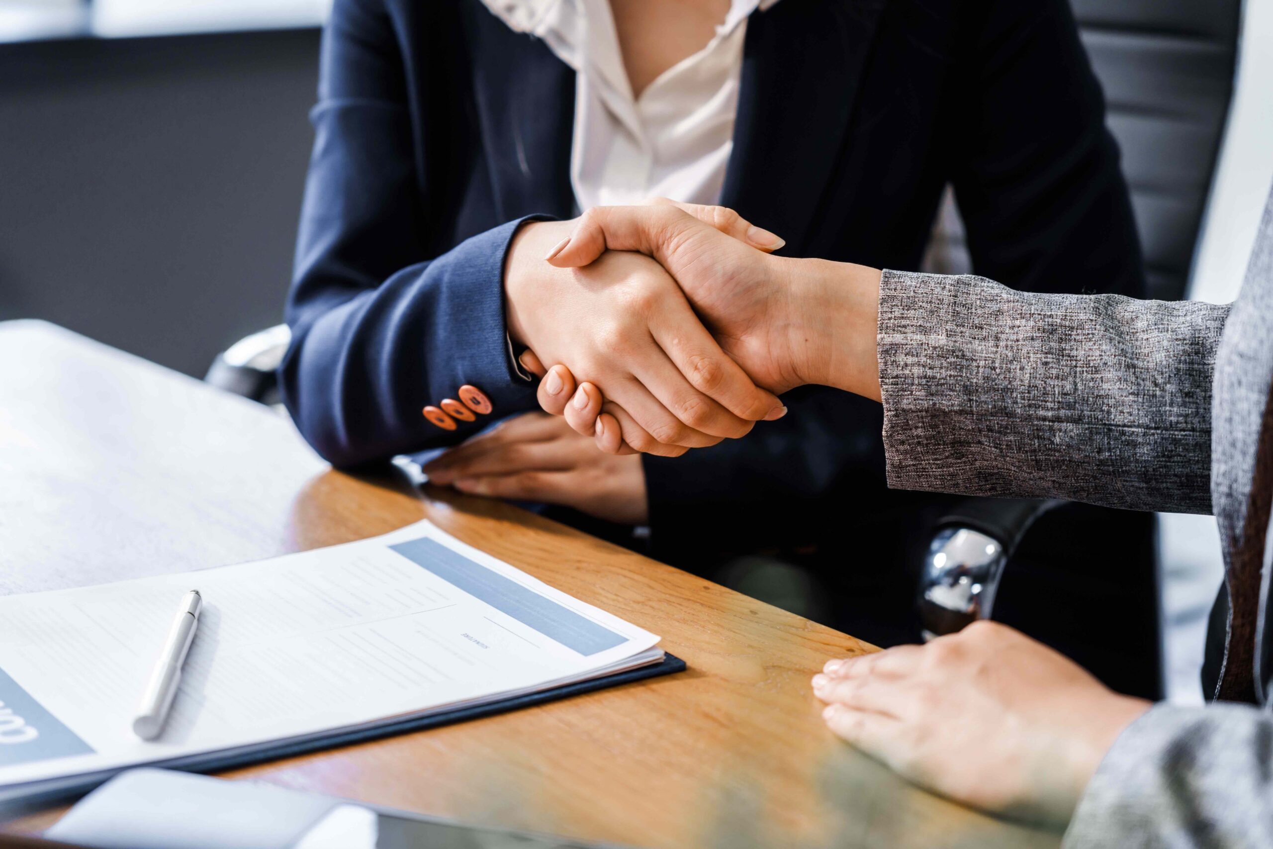 Two female lawyers in business suits shake hands